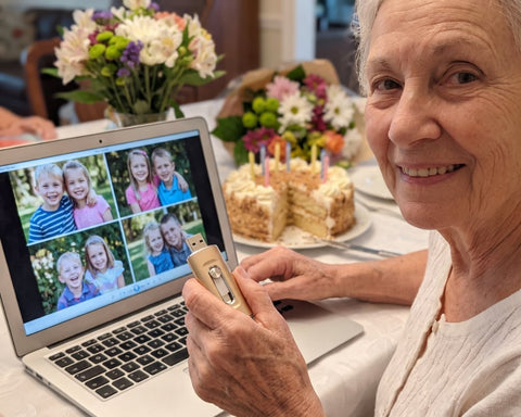 Ältere Frau hält einen goldenen Fotostick am Geburtstagstisch